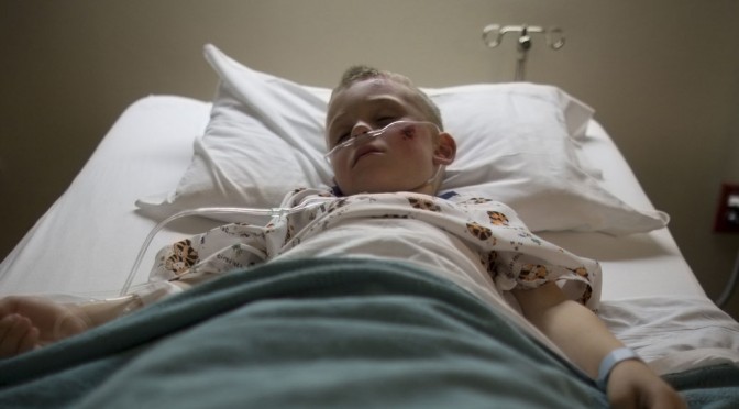 A sick child lies in a bed in a hospital